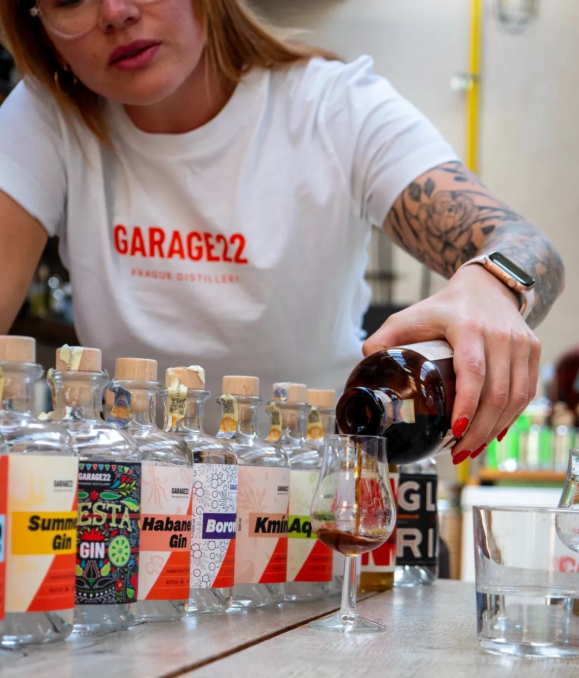 Simona z Garage22 nalévá do degustační skleničky před řadou lahví Garage22